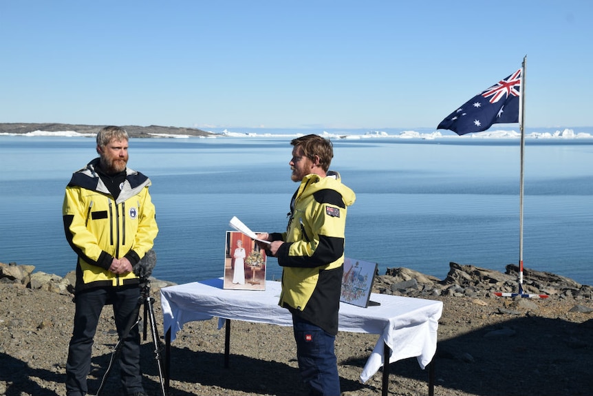 An Australian citizenship ceremony takes place at a small table on the edge of the water in Antarctica.