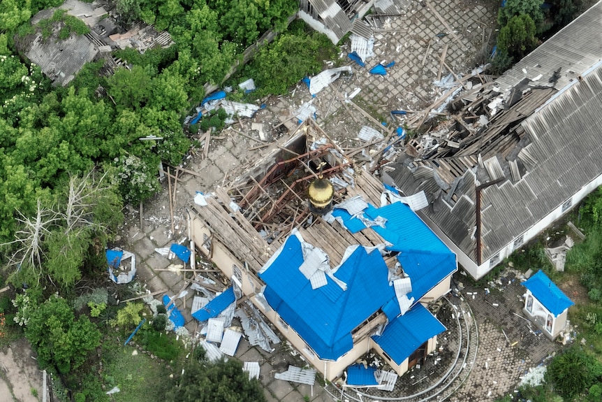 An aerial view of a ruined church ith partially blue roof.