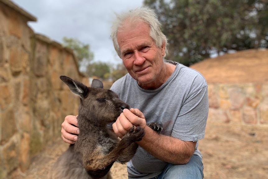 A man holds a kangaroo by the nose