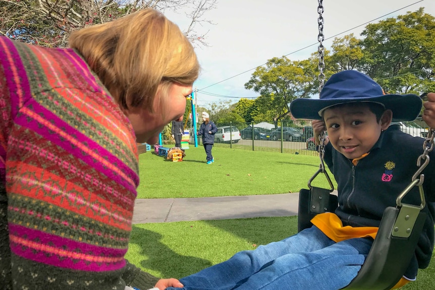 7 year old Andreas plays on the swing with his teacher at Giant Steps School