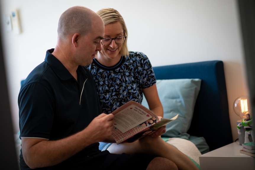A Caucasian couple read a children's book in a kid's bedroom