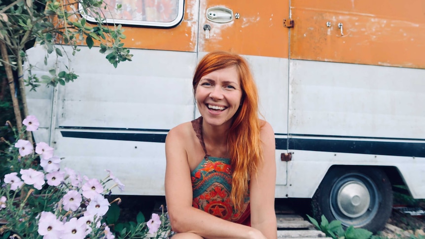 Lucy Aitken smiles in front of a caravan in a story about giving up shampoo and doing the no-poo method.