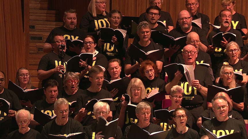 Vanessa Hughes and Damien Beaumont sing in a group of other choristers at the Sydney Opera House.