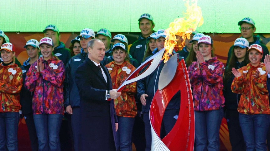 Vladimir Putin holds a lighted Olympic torch