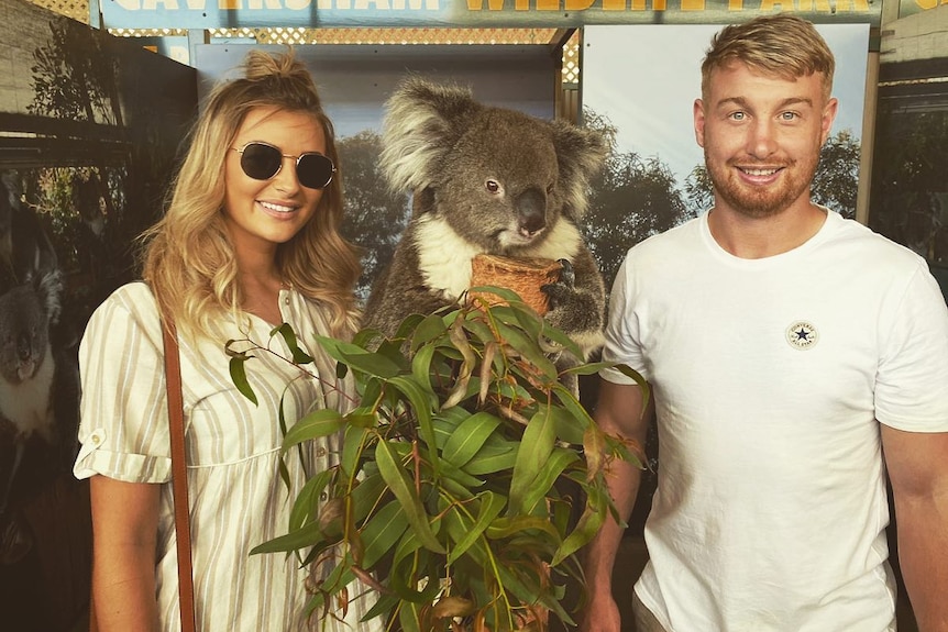 A man with blonde hair together with a woman with blonde hair and a koala.