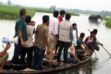 Environment officers look on as an elephant stands in flooded terrain in Bangladesh.