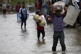 People carry their belongings as they wade across a flooded street while Hurricane Matthew passes through Port-au-Prince, Haiti.