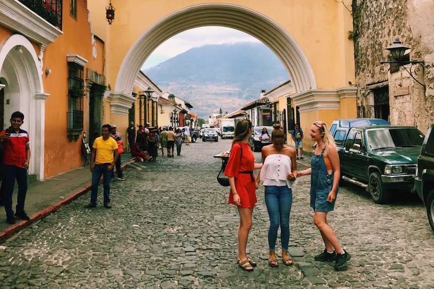 A group of women pose for a photo in front of a clock in Antigua.