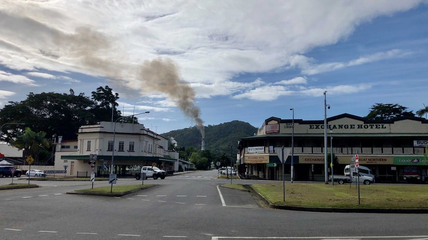 Steam emits from the chimney stack of a sugar mill clearly visible from the main street of the far northern town of Mossman