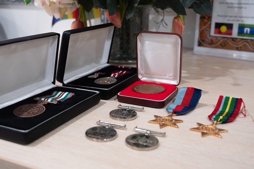 Several military medals on a table. Some are in boxes
