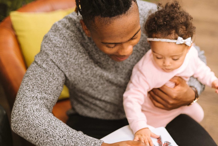 Smiling dad drawing with his infant daughter while holding her