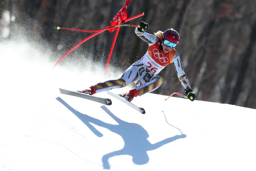 Un esquiador alpino vuela más allá de algunos palos de marcador en la nieve.