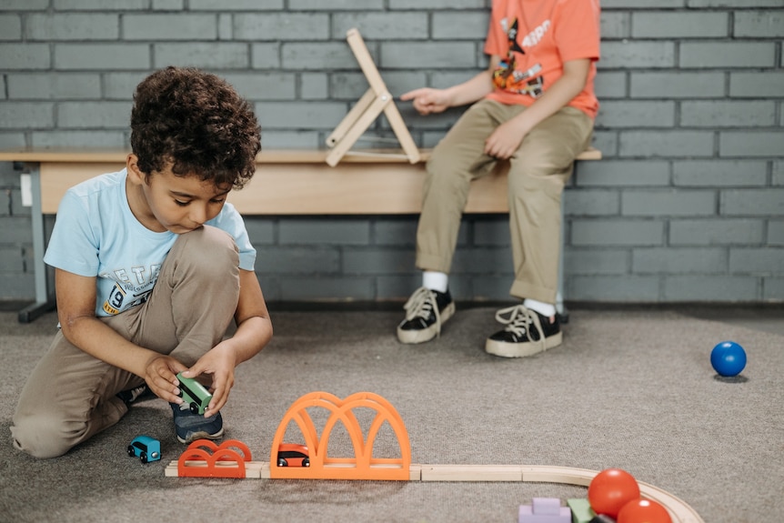 A young boy play with trains for a story on early puberty in children.