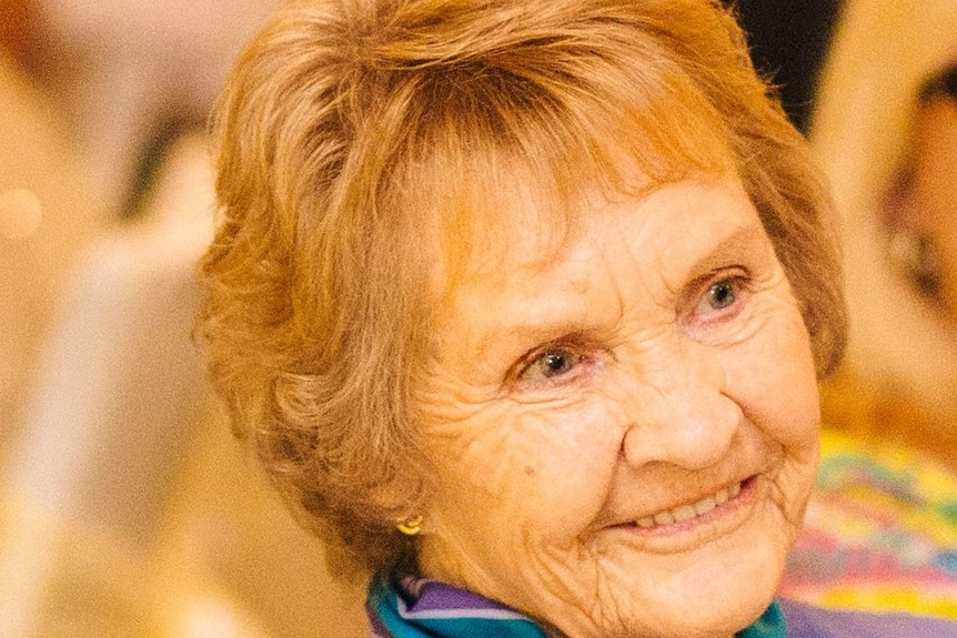Close-up of an elderly woman with a purple jacket and scarf