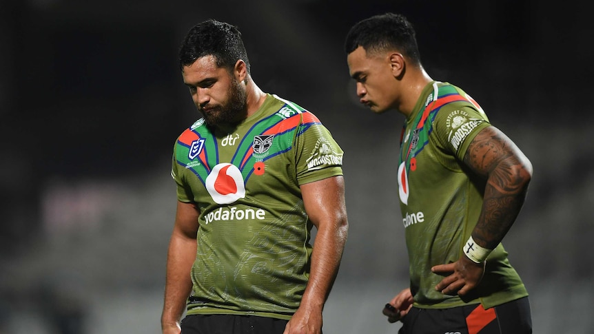 Peta Hiku and Ken Maumalo stand, wearing green shirts, looking down at the ground