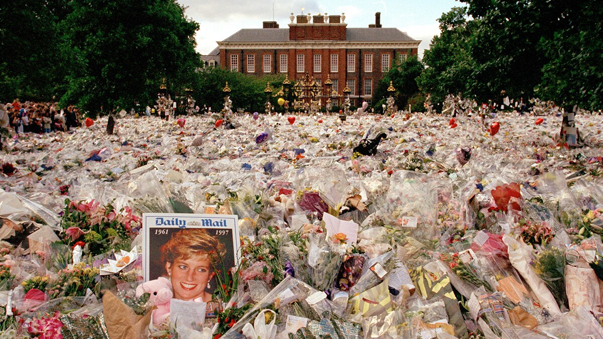 Thousands of flowers laid on the pavement leading to Kensington Palace;  a newspaper featuring Princess Diana in the foreground