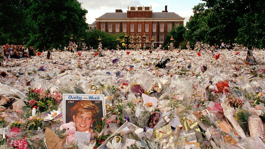 Thousands of flowers laid on the pavement leading to Kensington Palace; a newspaper featuring Princess Diana in the foreground