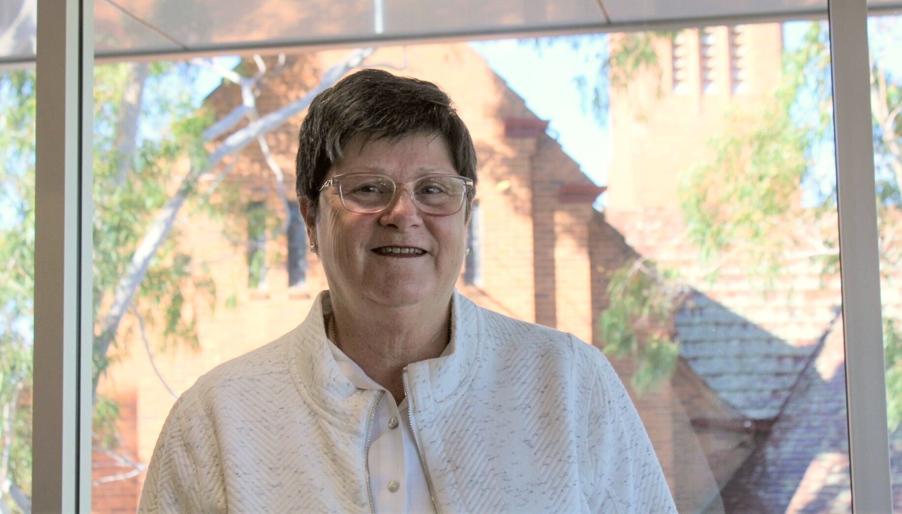 A woman in a white shirt smiles at the camera.