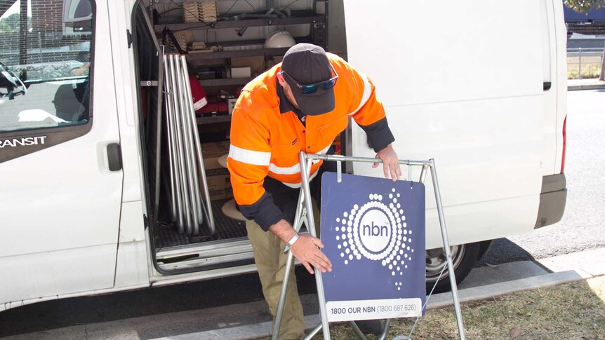 Michael Webeck packs away a sign displaying the NBN
