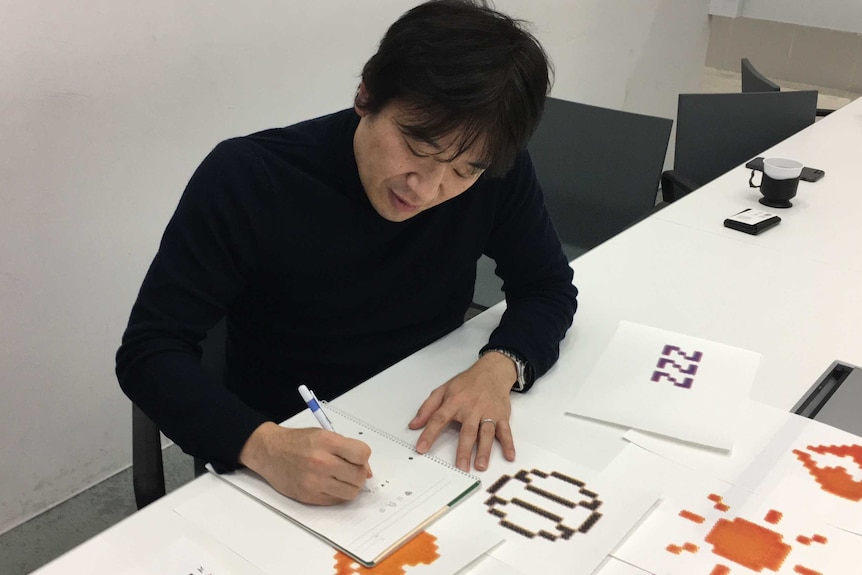 Emoji inventor Shigetaka Kurita draws in a notepad at MoMA, New York.