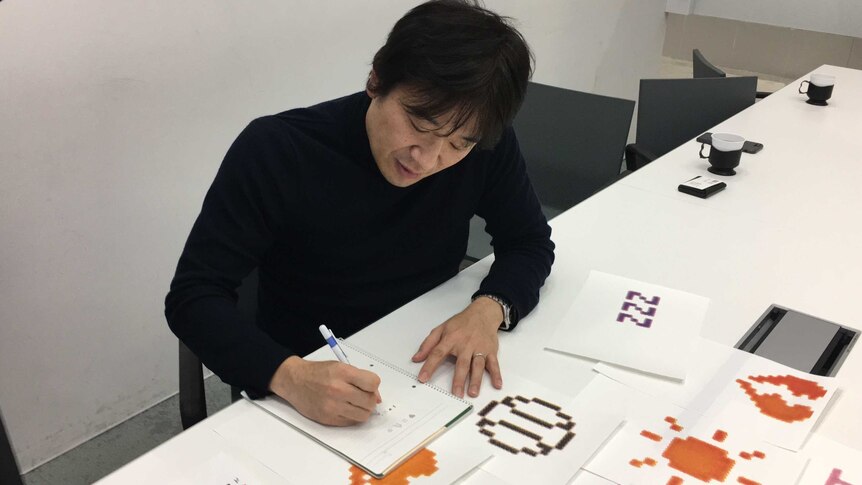 Emoji inventor Shigetaka Kurita draws in a notepad at MoMA, New York.