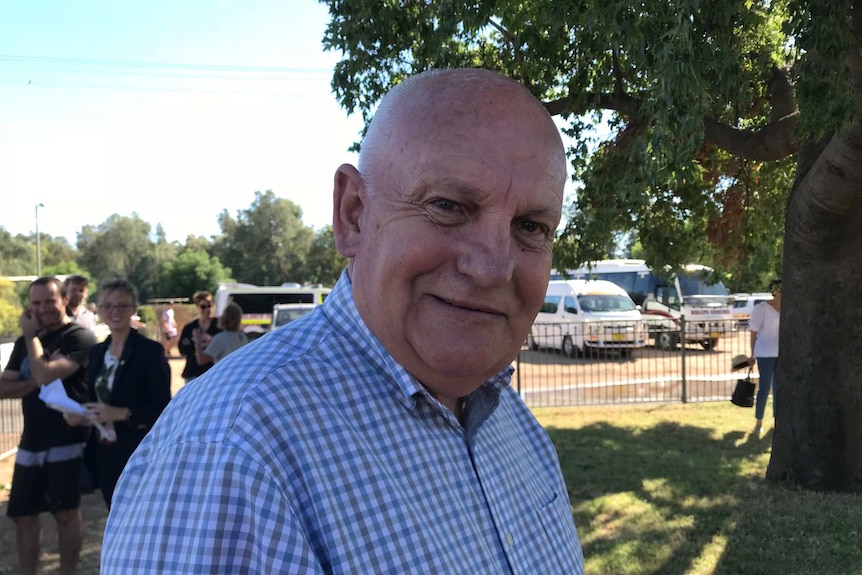 A bald man in a checked shirt smiles at the camera.