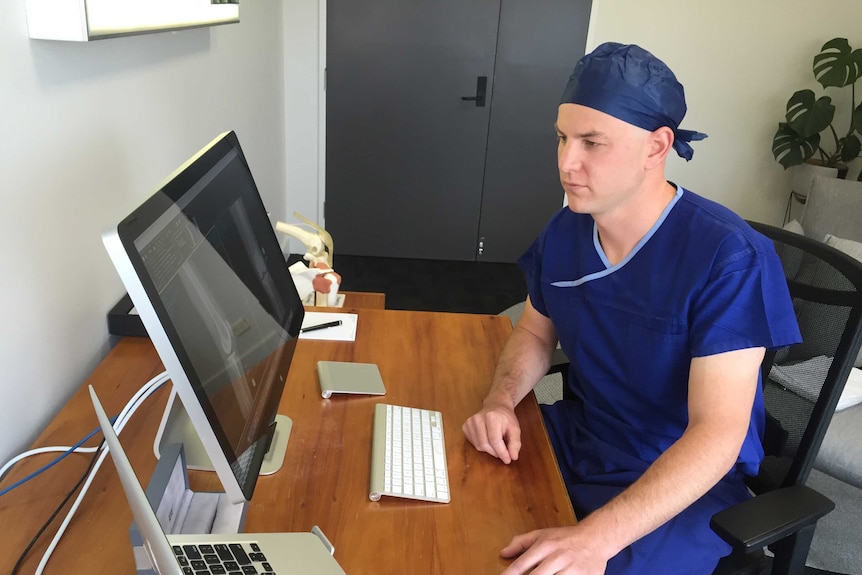 Orthopaedic surgeon, Josh Petterwood looks at a computer in his office.