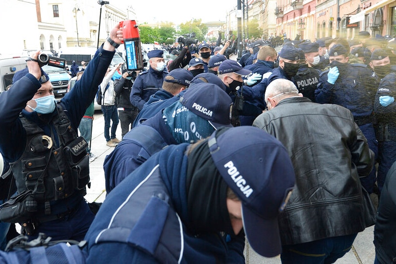 Police are pictured firing tear gas over a crowd of protesters demanding an end to restrictions.