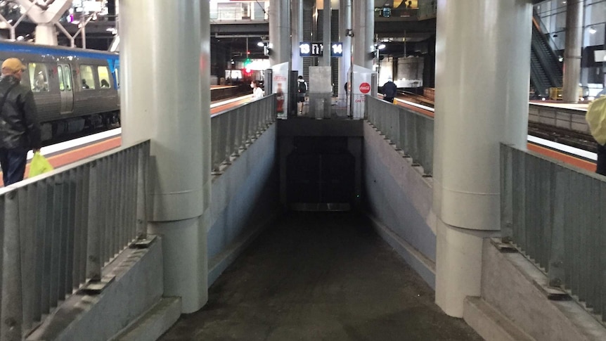 a ramp on a station platform leading down to a closed double door
