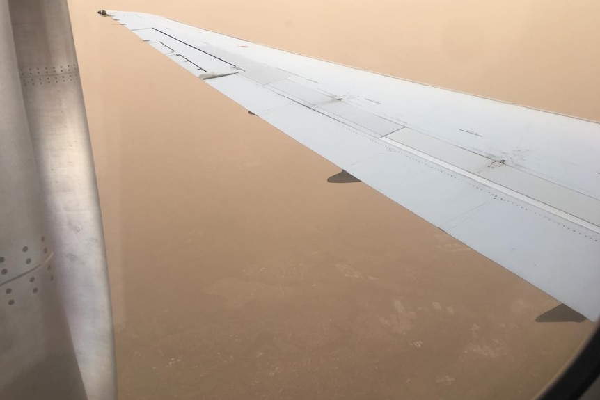 Picture taken out of a plane window. You can just seen the houses peaking out through the dust.