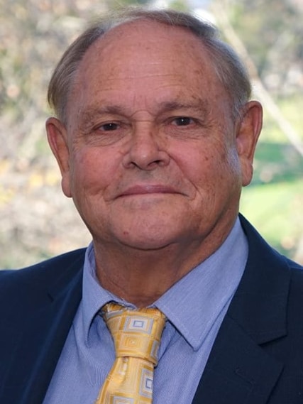Headshot of a First Nations man in a light blue shirt with dark blue suit jacket and yellow tie 