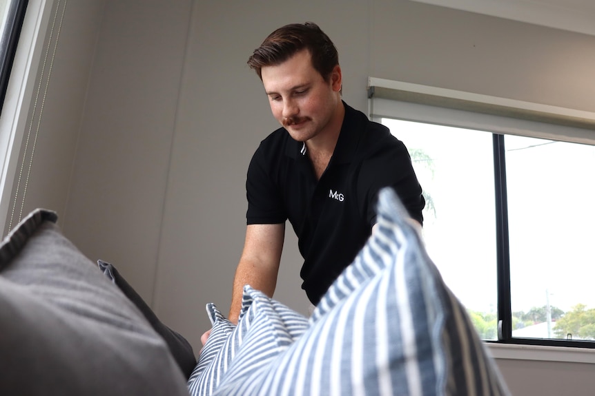 Man adjusts pillows on a bed