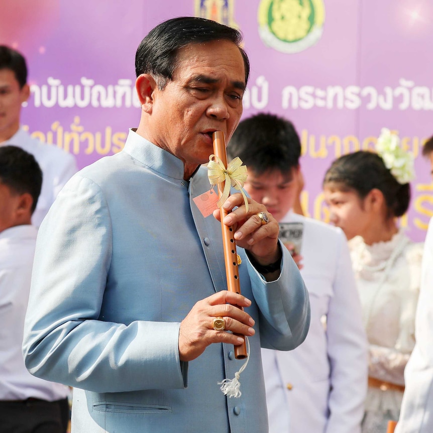 A man in traditional Thai dress plays the flute