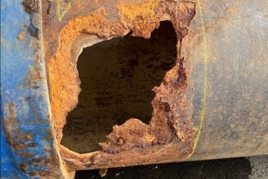 A large hole in a rusted pipe.
