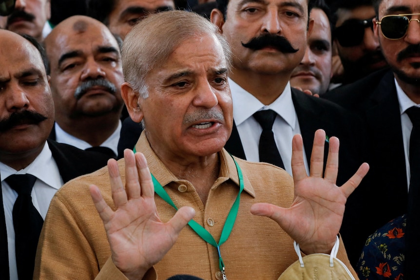 A photo of a man holding up his hands and gesturing while talking