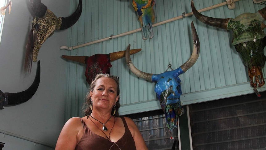 A photo of Nicola Collins in her studio, with multiple buffalo heads visible in the background.