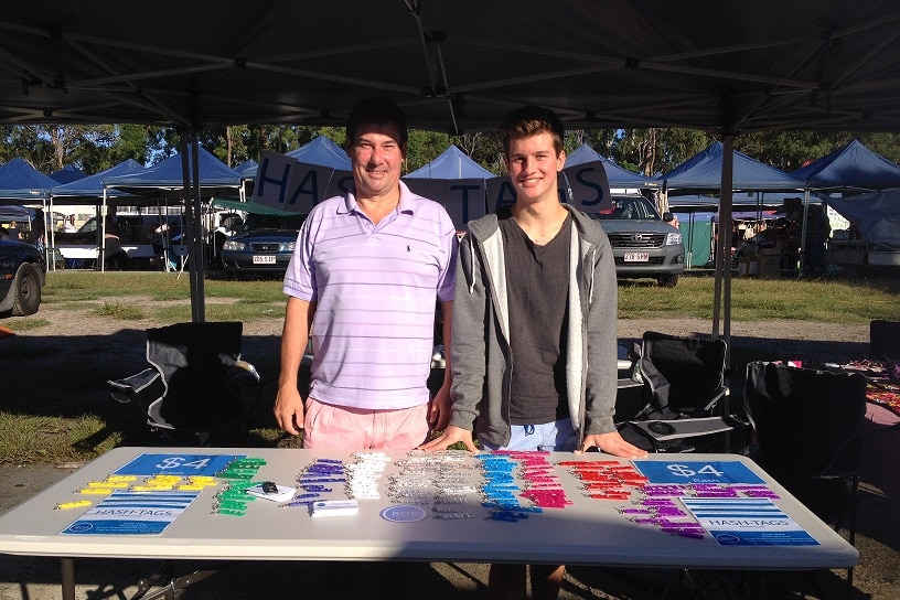 Scott and his dad selling the hashtag key rings at a market stall.
