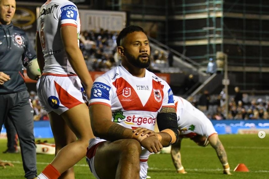 A rugby league player kneels while on the field