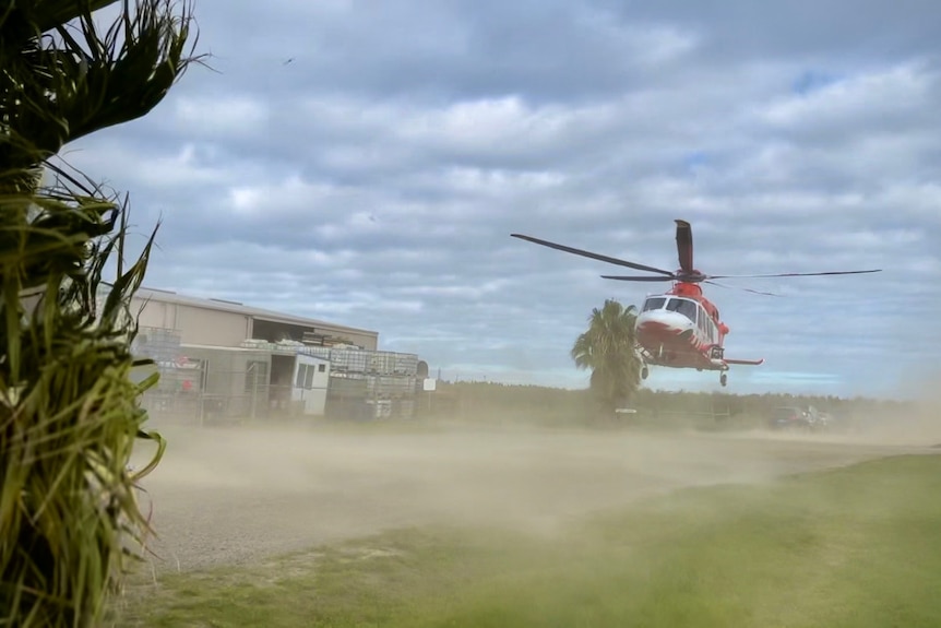A helicopter stirs up dust as it takes off.