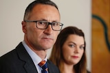 Greens leader Richard Di Natale, looking terse, stands in front of Sarah Hanson-Young.