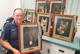 Sergeant Bill Applebee sits with framed portraits of the six other police dogs he has had over 43 years as a police officer.