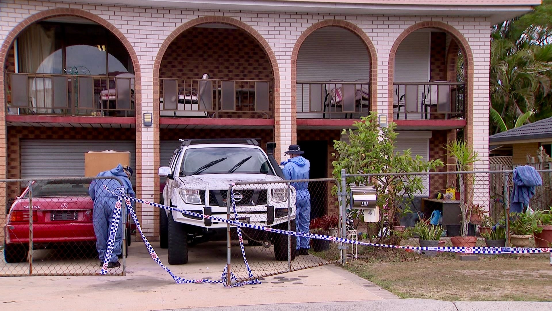 forensice officers at a house cordoned off with police tape