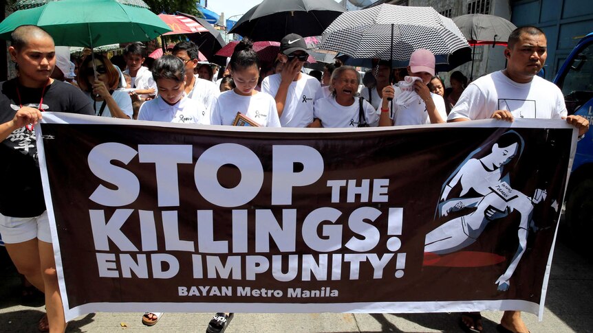 Protesters hold up a banner calling to stop the continuing rise of killings.