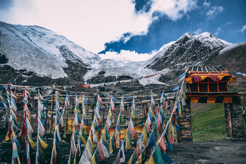 Tibetan wall and prayer flags on top of a snow covered mountain