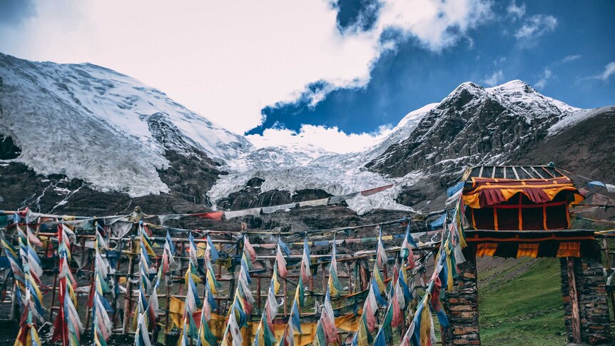 Tibetan wall and prayer flags on top of a snow covered mountain