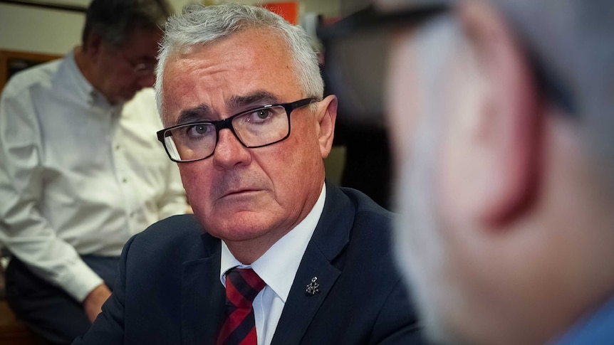 Independent MP Andrew Wilkie stares intently at a person out of focus.