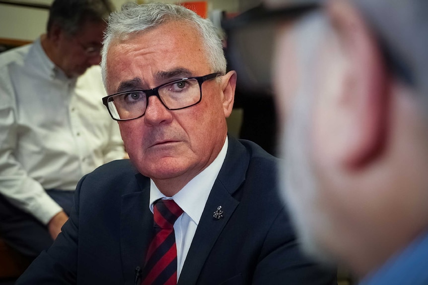 Independent MP Andrew Wilkie stares intently at a person out of focus.