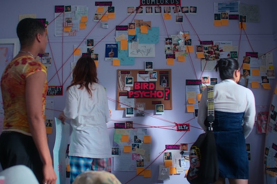 Three teens stand in front of an elaborate evidence board with the words "bird psycho?" in the middle. Red string links photos.