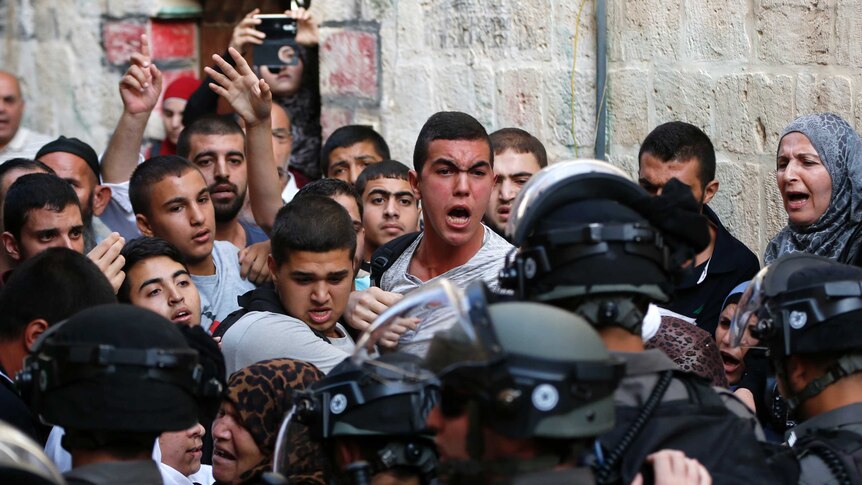 Palestinians shout in front of Israeli security forces who block a road leading to the Al-Aqsa mosque compound in Jerusalem's Old City