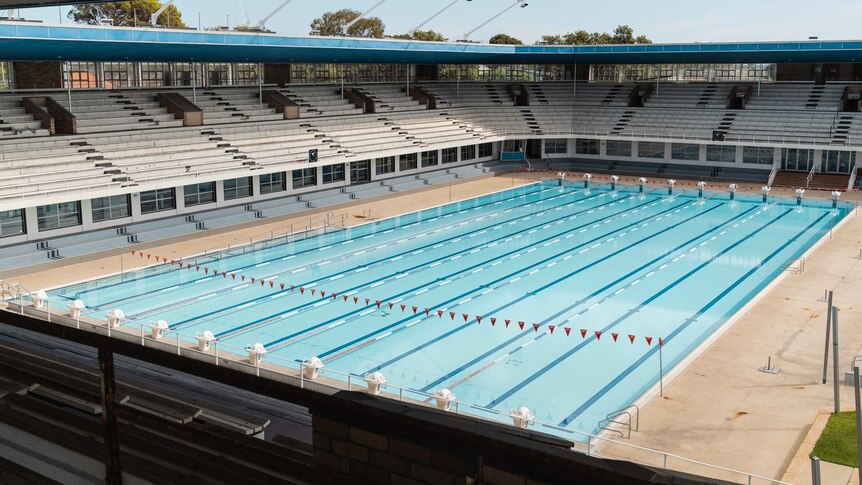 A picture of a still Olympic sized swimming pool taken from a grandstand